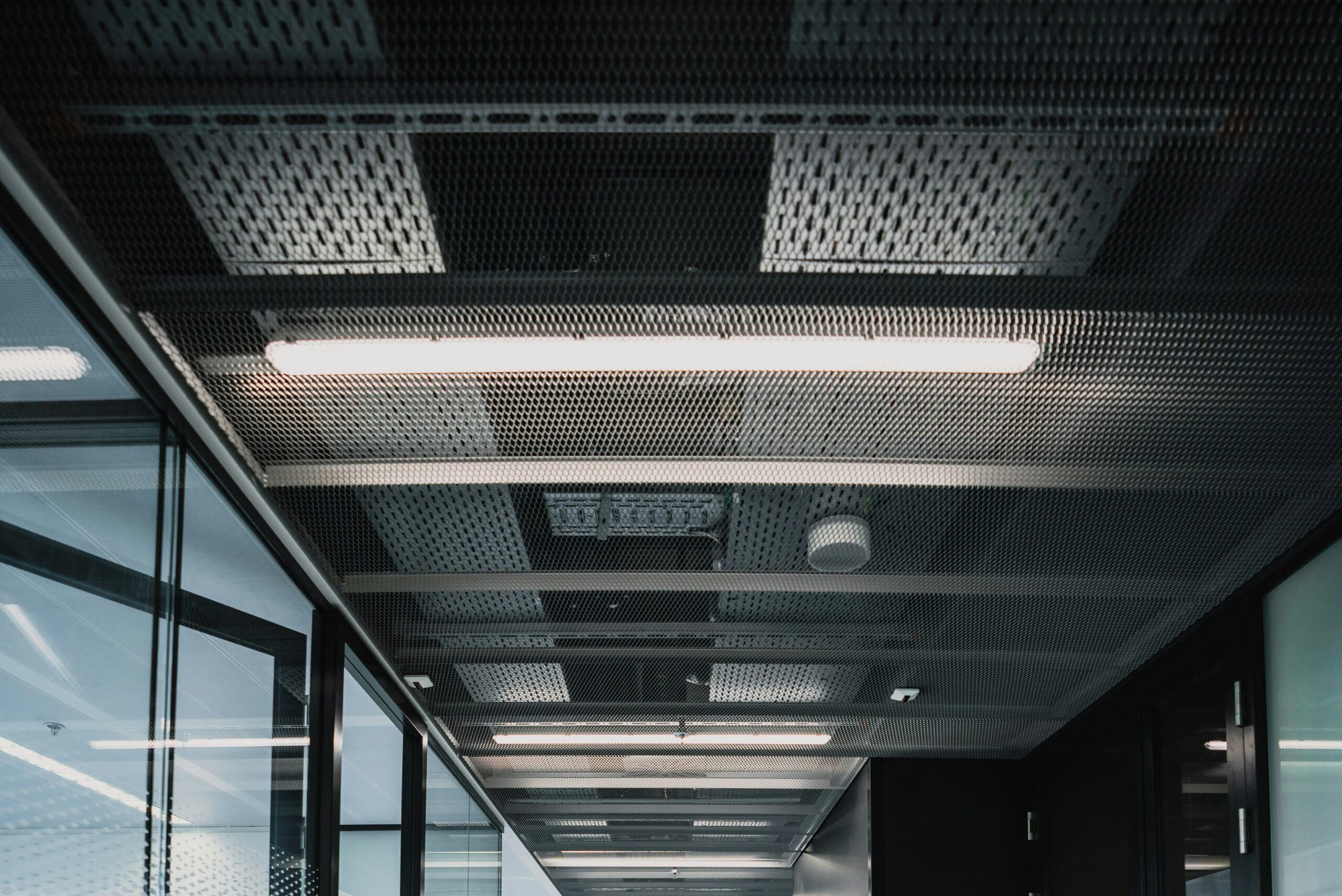 Hal met modules zichtbaar aan het plafond. Deze kant-en-klare kooiconstructies van montagerails met leidingen worden in de prefab-werkplaats in Hengelo gemaakt.