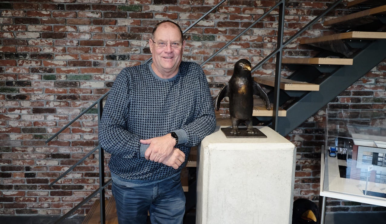 Wim Stouthart in de entree van het bedrijf dat hij 25 jaar geleden begon. De pinguïn naast hem is ook te vinden in het logo van het bedrijf. Net als klimaatinstallaties - de specialiteit van het bedrijf - is het dier goed in warmte opnemen en afgeven.